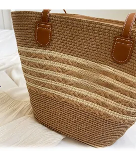 Détail d'un sac cabas en paille tressée avec anses en cuir marron et rayures