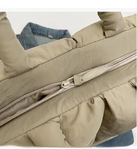 Close-up of smooth metal zipper and padded quilted texture on khaki tote bag
