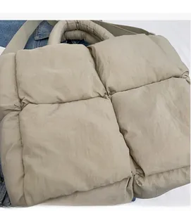 Close-up of beige quilted tote bag showing soft padded fabric texture and large grid pattern