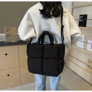 Detail of black quilted puffer tote bag with thick handles and adjustable shoulder strap
