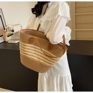 Détail d'un sac cabas en paille rayé avec anses en cuir marron sur fond de style de vie