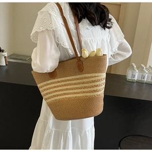 Détail d'un sac cabas en paille tissé à la main avec rayures crème et anses en cuir