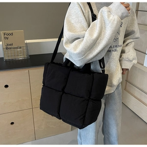 Close-up of quilted black tote bag showing puffer texture and adjustable shoulder strap