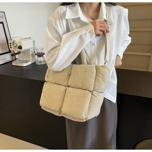 Detail of beige quilted tote bag with adjustable strap worn as a crossbody commuter bag