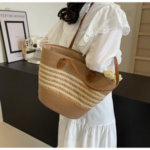 Détail d'un sac cabas en paille tressée à rayures crème avec anses fines en cuir brun