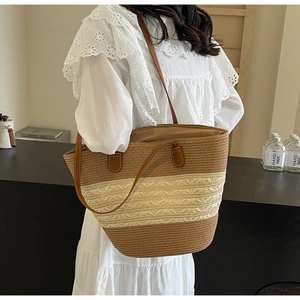 Détail d'un sac cabas en paille avec lanières en cuir marron et texture rayée