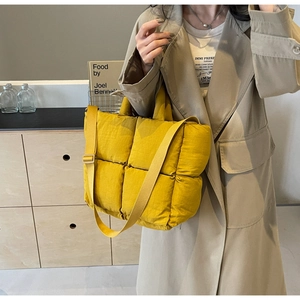 Detailed close-up of yellow quilted nylon tote bag with puffer padding and adjustable strap
