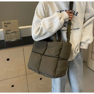 Detail of olive green quilted crossbody bag with padded texture and adjustable strap