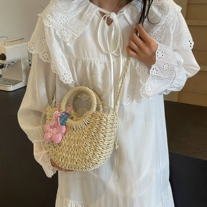 Handwoven straw crossbody bag with floral pendant and drawstring inner bag for beach vacation
