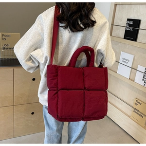 Detail of burgundy quilted puffer tote bag showing soft padded texture and strap