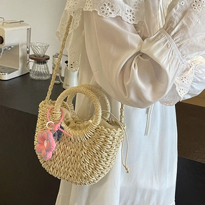 Handcrafted woven straw bucket bag with floral charm and drawstring lining for summer beach