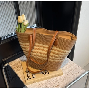 Détail du sac cabas en paille tissée avec anses en cuir marron et rayures