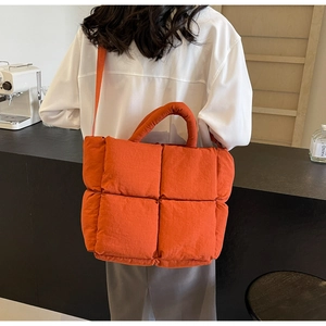 Macro detail of large orange quilted tote bag with soft padded texture and stitching