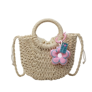Handwoven beige straw handbag with semi-circle design and pink flower charm pendant