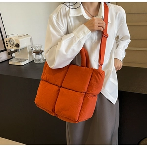 Detailed view of the bright orange quilted tote bag with square texture and woven strap
