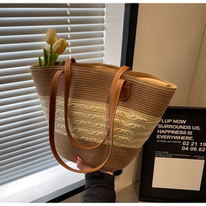 Détail du sac cabas en paille rayé avec poignées en cuir marron et texture tissée
