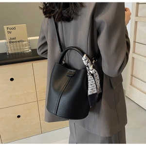 Detailed view of black pebbled leather bucket bag with geometric silk scarf and leather handle