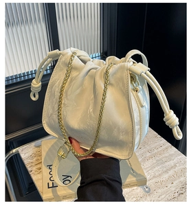 Detail of ivory ruched cloud bag featuring gold chain handle and textured faux leather
