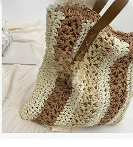 Vue détaillée du sac en paille rayé avec bandoulière en cuir et coutures en croix