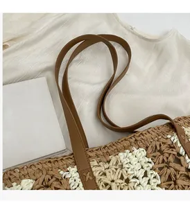 Détail des anses en similicuir marron avec coutures en X renforcées sur le sac en paille