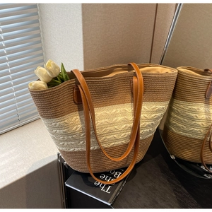 Détail du sac cabas en paille tissée avec rayures marron et crème et anses en cuir robuste