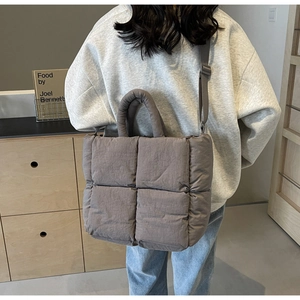 Detailed view of grey quilted tote bag with cross-body strap and soft padded material