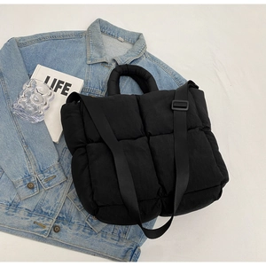 Detail of black quilted puffer tote bag with soft texture and adjustable wide shoulder strap