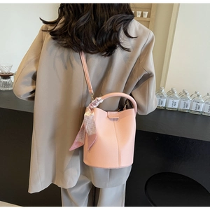 Pink soft leather bucket bag with decorative silk scarf shown on person for style reference