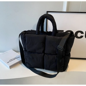Macro detail of black quilted nylon tote bag with plush texture and wide shoulder strap