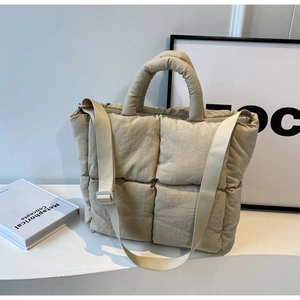 Close-up of beige quilted down tote bag showing large square stitching and soft nylon texture