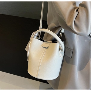 Detail of off-white lychee texture leather bucket bag with printed silk scarf handle