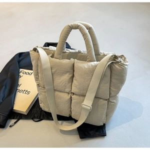 Detail of beige quilted tote bag showing padded texture and adjustable strap on leather jacket