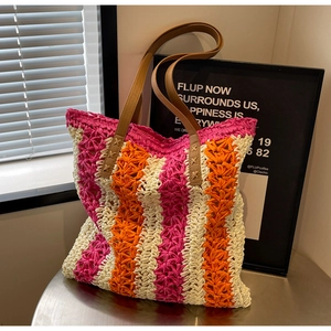 Détail du sac cabas en paille rayé avec lanières en cuir marron et coutures en croix