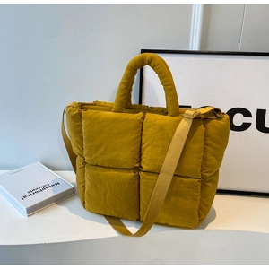 Macro detail of mustard yellow quilted puffer tote bag with thick padded handle and strap