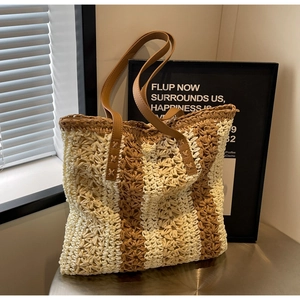 Détail du sac cabas en paille rayé avec anses en cuir marron et coutures renforcées