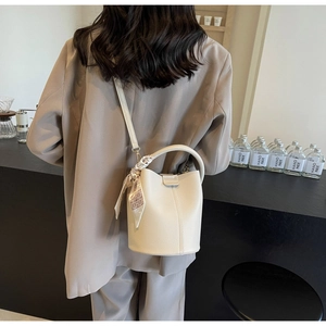 Detail of white lychee leather bucket bag with silk scarf on a stylish beige blazer suit