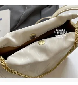 Detail of off-white bucket bag featuring invisible magnetic closure and gold chain strap