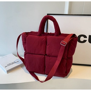 Detail of burgundy quilted tote bag with padded texture and adjustable strap