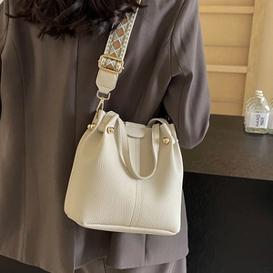 Sac seau beige chic avec bandoulière tissée large et cuir grainé sur mannequin