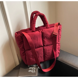 Detail of red quilted tote bag with padded texture and adjustable fabric shoulder strap
