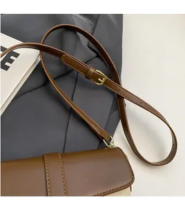 Detail of adjustable brown leather shoulder strap with gold buckle on retro bucket bag