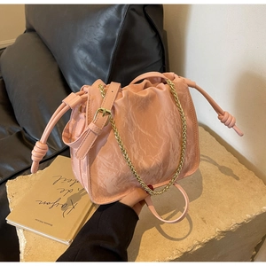 Detailed view of pink pleated cloud bag with gold chain and leather shoulder strap