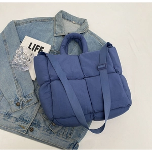Close-up of quilted dark blue puffer tote bag with adjustable strap and soft texture