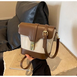 Detail of vintage bucket bag with brown leather trim, white woven fabric, and gold clasp
