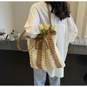 Détail d'un sac cabas en paille tressée avec rayures et bandoulière en similicuir