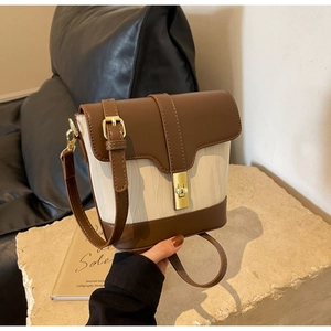 Detail of vintage bucket bag with brown leather, beige fabric, and gold clasp on stone
