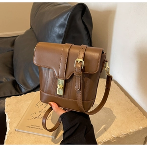 Detail of brown vintage bucket bag featuring V-shaped woven texture and gold metal lock