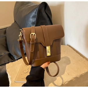 Detail of brown leather bucket bag featuring wavy embossed texture and gold metal twist lock