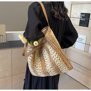 Détail d'un sac à bandoulière en paille tissée avec anses en cuir sur une étagère