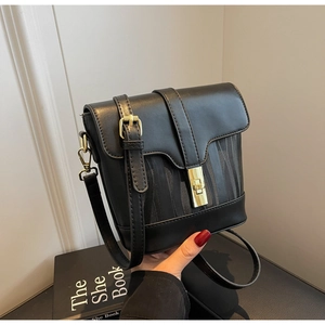 Detail of black crossbody bucket bag featuring gold square twist lock and textured fabric